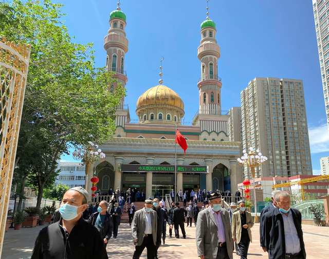 金曜礼拝を終え、モスクから出てくるウイグル族ら少数民族の人々。広場には中国国旗が掲げられている=2021年5月21日、ウルムチ、高田正幸撮影