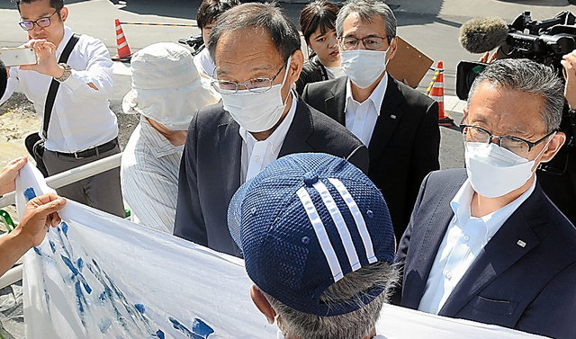 上関町役場前を訪れた中国電力幹部らが「使用済核燃料おことわり」の横断幕を持った市民らに進入を阻まれた。怒号が飛ぶ中、通用口から役場に入った＝いずれも２日