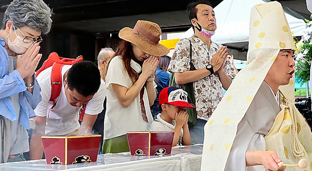 京橋駅空襲の慰霊祭で、祭壇に向かい手を合わせる参列者たち＝２０２３年８月１４日午前、大阪市内、長富由希子撮影