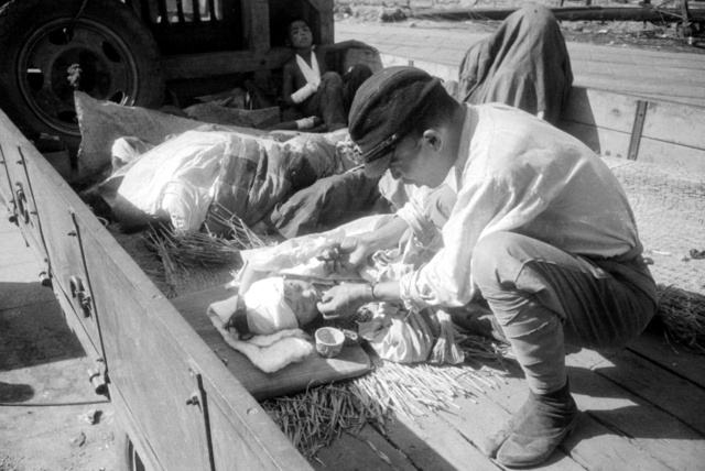 現在の広島市中区付近で、トラックの荷台に横たわった少女の口元に救援隊員が食べ物を近づける=1945年8月10日、宮武甫氏撮影