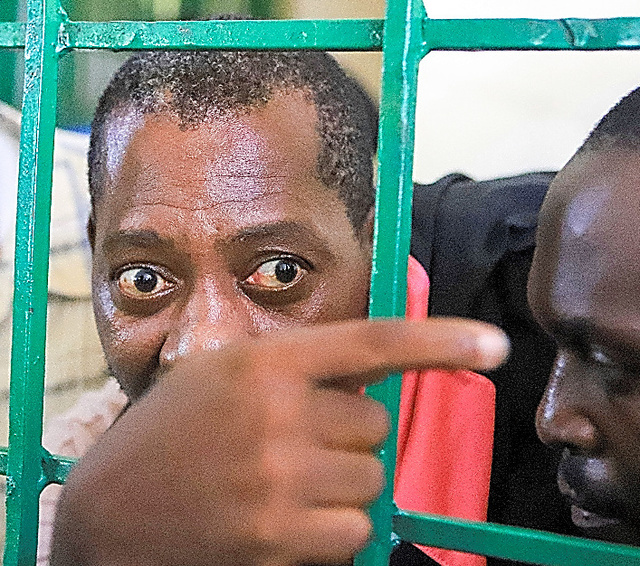 ケニア東部モンバサの裁判所で５月、鉄格子の間からのぞき見るポール・マッケンジー容疑者＝ロイター