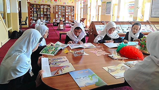学校図書館で絵本を読む女の子たちの様子＝２０２３年８月、アフガニスタン東部地域で。シャンティ国際ボランティア会（ＳＶＡ）提供