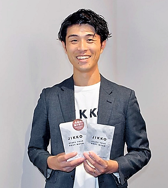健美薬湯５代目社長の松田宗大さん。手に持っているのが入浴剤の新しいパッケージ