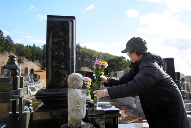 行方不明の女子部員のお墓に花を供える畠山由紀子さん=2023年12月、岩手県陸前高田市、三浦英之撮影