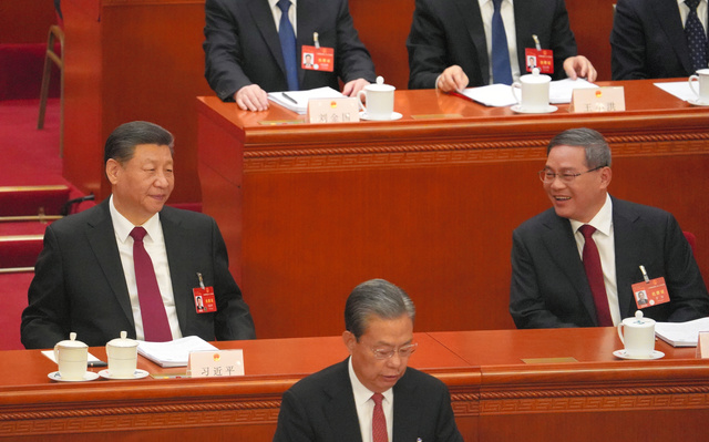 全人代が開幕した2024年3月5日、政府活動報告の読み上げを終えたあと、笑顔を見せる李強首相（右）。左は習近平国家主席=北京の人民大会堂、井上亮撮影