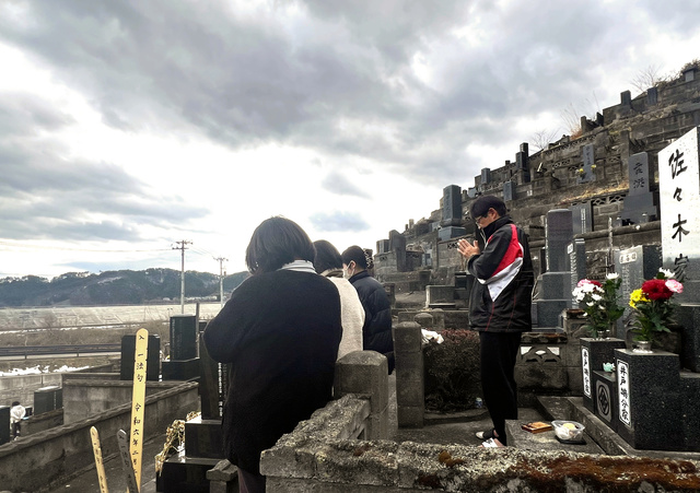 地震が起きた午後2時46分、佐々木彰さん（右）は、津波で行方不明のままの両親の墓の前で、海に向かって手を合わせた=2024年3月11日、岩手県大槌町、野津彩子撮影