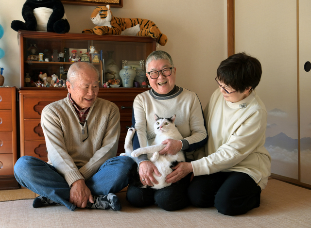 飼い主を亡くした「てんちゃん」はいま堀池さん夫妻のもとで暮らす。吉本由美子さん（中央）は「シニア猫の扱いに慣れている方にお任せでき、安心です」と笑顔を見せる=大阪府泉大津市、滝沢美穂子撮影