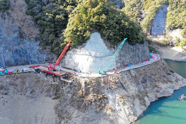 土砂崩れが起きた現場では、応急対策として橋をかける工事が進む=3月18日、奈良県下北山村、ドローンで撮影、県提供