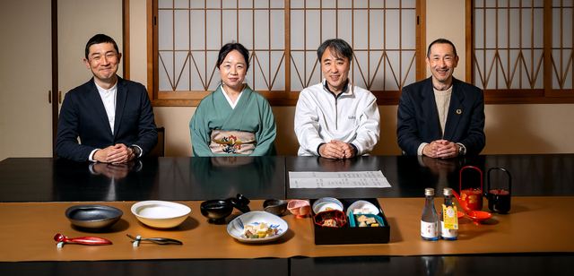 見た目も美しくおいしい嚥下食などを開発してきたメンバーたち。右から２人目が荒金英樹さん。前に並ぶのは、右からとろみつき日本酒「斗瀞酒（ととろさけ）　雅香（みやこ）」、「やわらか京料理」、すくいやすく工夫された介護食器＝京都市の「京料理せんしょう」