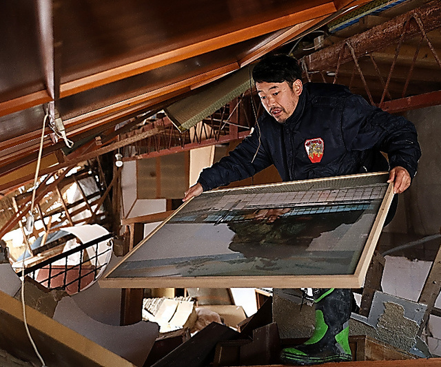 倒壊した本館に入り、２階部分に挟まっていた写真パネルを取り出す橋元宗太郎さん＝２月２６日、石川県珠洲市