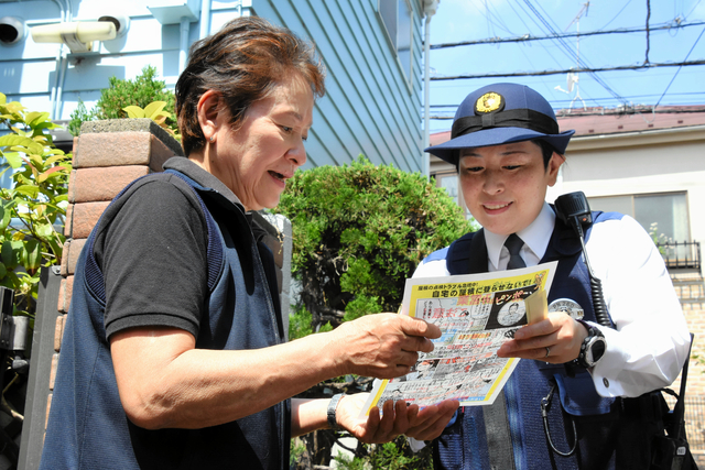 警視庁の警察官（右）が訪れ、住民の女性に悪質リフォーム業者について説明した=2024年4月26日午前10時10分、東京都、御船紗子撮影