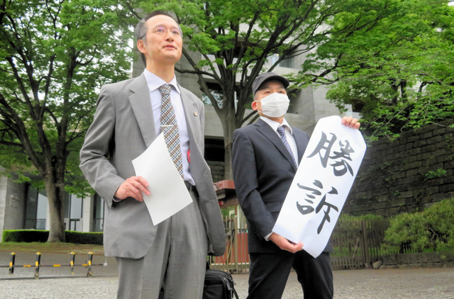 最高裁の判決後に「勝訴」と書かれた紙を掲げる原告（右）=2024年4月26日午後、東京都千代田区