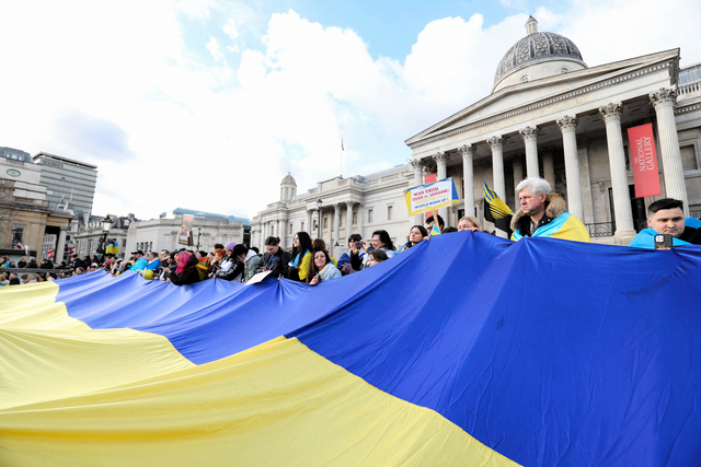 ロシアによるウクライナへの全面侵攻が始まって2年となった2024年2月24日、ロンドンでウクライナ国旗を掲げる人びと=ロイター