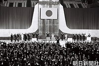 ５月１５日、政府主催の沖縄復帰記念式典で、佐藤栄作首相（手前中央）の発声で万歳三唱する昭和天皇、香淳皇后と参列者たち。皇太子さまは１９７５年の沖縄海洋博で沖縄県訪問を果たすことになる