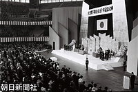 １１月１０日、東京・日本武道館で開かれた政府主催の昭和天皇在位５０年記念式典で、お言葉を述べる昭和天皇と香淳皇后。奥に皇太子さまと常陸宮さま、手前に美智子さまと華子さまがお立ちになっている