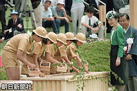京都府宇治市で開かれた第４２回全国植樹祭で、お手まき所に種をまく「緑の少年団」を見守る皇后さま。右は荒巻禎一京都府知事
