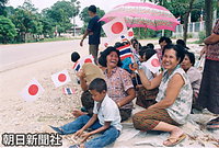 タイ王朝発祥の地・スコータイで、シートを敷いて天皇、皇后両陛下の車列を歓迎するために随分前から待っている人たち