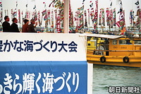 愛媛県伊予市の森漁港で行われた第１３回全国豊かな海づくり大会で、大漁旗を掲げた漁船のパレードに手を振る天皇、皇后両陛下