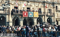スペイン・サマランカ市庁舎前広場で、日の丸の小旗を手に天皇、皇后両陛下を歓迎する人たち。両陛下はバルコニーから手を振ってお応えになっている