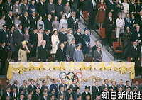１０月１０日、東京オリンピックの開会式に臨む昭和天皇。右は香淳皇后、後ろに常陸宮さまと華子さま。左は皇太子さまと美智子さま、秩父宮妃勢津子さま。右は高松宮さまと喜久子さま、三笠宮さまと百合子さまが立つ