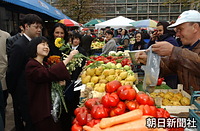 ブカレスト市内のアムゼイ市場を訪れ、野菜や果物を売る商店から菊などの花を贈られ、笑顔をみせる紀宮さま。露店には洋梨やパブリカ、ニンジンなどが積み上げられている