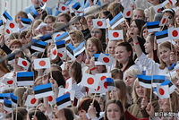 ステージに立ち、日の丸とエストニア国旗を振って両陛下を歓迎する合唱団