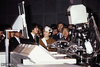 つくば科学万博会場で、電子ピアノ演奏ロボット・ワスボットくんを見学される皇太子さまと美智子さま、礼宮（秋篠宮）さま。このロボットはいまも、つくばエキスポセンターに展示されている
