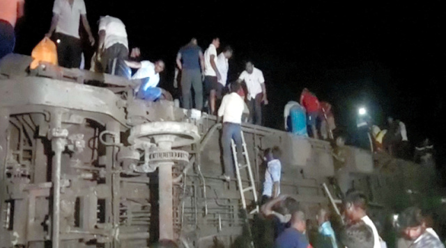 インド東部のオリッサ州で2023年6月2日、衝突事故を起こした列車から乗客を救助しようとする人々=ロイター