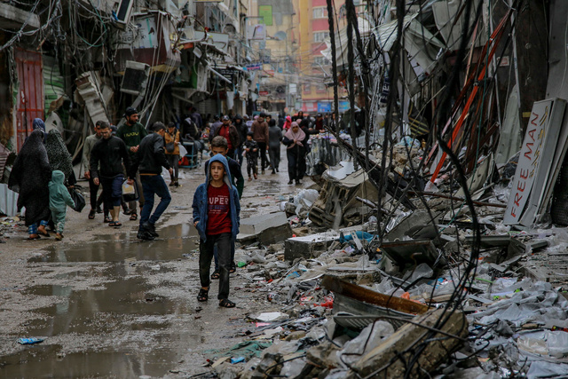 2023年11月27日、ガザ市の市場付近で、破壊された建物の間を歩く少年=AFP時事