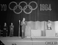 ６月　１９６４年（昭和３９）東京五輪開催に向けたオリンピックデーの催しで、お言葉を述べる皇太子さま。右は美智子さま、後方右は池田勇人首相