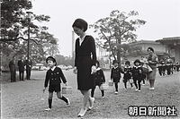 ３月、東宮御所に学習院幼稚園で一緒の園児たちを招いた際に、美智子さまと一緒に案内するバスケットを手にした浩宮さま。右後ろでハンドバッグを持っているのは担任の大熊ヨネ子先生