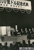 ６月、貿易記念日に開かれた輸出１００億ドル記念式典であいさつする皇太子さま。後ろは美智子さまや佐藤栄作首相ら。東京・日比谷公会堂で