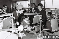 ７月、東京都心身障害者福祉センターを訪れ、タイプライターを打つ女性に話しかける皇太子さまと美智子さま