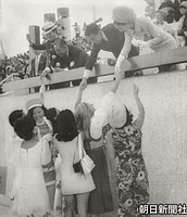 ９月１３日、日本万国博が閉幕し、お祭り広場で行われた各展示館のホステスによるパレードで、貴賓席に駆け寄り皇太子さまと美智子さまに花を手渡し握手する女性たち。左の佐藤栄作首相もにこやかだ