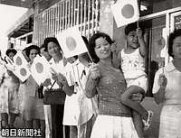ひめゆりの塔近くで日の丸を手に笑顔で歓迎する人たち。沖縄でも本土と変わらずに皇太子ご夫妻の訪問先で見られた。１７日は沿道に約６万８００人の住民が歓迎に立った