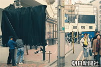 東京・渋谷で派手な色の目立つ看板を黒いビニールで覆う広告業者の作業員