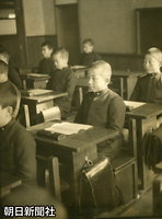 １９４５年１２月、学習院初等科の教室で授業を受ける天皇陛下。机の脇の掛け金にランドセルを下げている