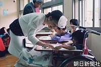 沖縄市の「沖縄小児発達センター」（現・沖縄中部療育医療センター）を視察し、子供たちにやさしく声をかける皇后さま 。ジャケットの裾とスカートに琉球絣をアレンジされた「琉球ファッション」をされている