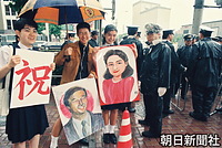 沿道で皇太子さまと雅子さまの似顔絵を手に持つ学生たち