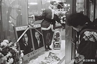 東京・銀座にある小松ストアーのショーウインドーでは、皇太子さまと正田美智子さんの肖像写真に、サンタクロースがカーネーションを捧げている。乳児を背負い、のぞき込んでいる女性はねんねこ姿