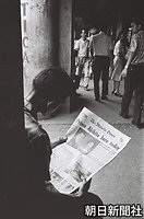 皇太子さまと美智子さまの写真を掲載したマニラの地元紙を読む男性