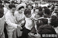 フィリピン大学では歓迎する学生たちに囲まれ、笑顔で握手の手を伸ばす皇太子さまと美智子さま
