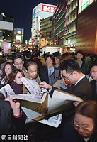 雅子さまのご出産の明るいニュースが街に流れ、東京・新宿駅前で配られる号外を受け取る人たち