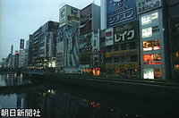 日が沈んでもネオンが消えたままの大阪・道頓堀。グリコの走る人も夜に沈んで見えた