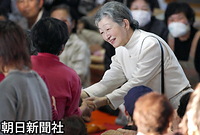小千谷市総合体育館で、ひざをついて住民の手を握り、笑顔で話される皇后さま