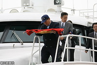博多港と玄界島を往復する福岡市営の渡船に掲揚するため、天皇旗を捧持して船首に向かう乗組員