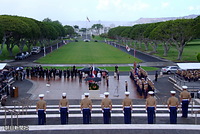 １５日、国立太平洋記念墓地で、スコールが降るなか供花される天皇、皇后両陛下。手前は礼砲を撃つために待機する儀仗隊の銃手たち。広場に向かって左に立っているのは随員、右奥にダイヤモンドヘッドが見える。ここ