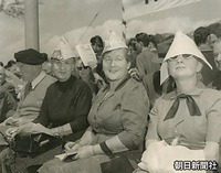国会前で、紙を折った帽子をかぶり日差しを避けながら見物する外国人たち