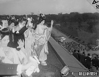 馬車で東宮仮御所へ向かう皇太子さまと美智子さまに手を振る、同日に挙式した新郎新婦、右後方は皇居・半蔵門