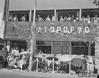 麹町で馬車列を店の２階で待つ外国人と歩道に座って待つ日本人